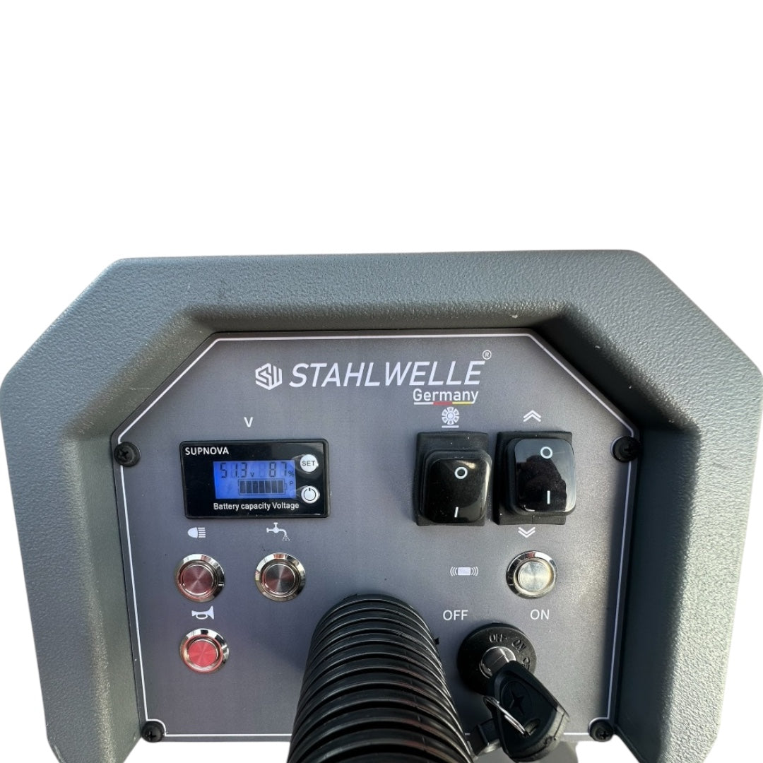 Een grijze Stahlwelle Germany E-800SW schrobzuigmachine, schuin van achteren gefotografeerd tegen een witte achtergrond. De machine heeft een duwboom met handvat voor bediening, wielen voor transport en een zwarte borstelkop aan de onderzijde. Het Stahlwelle logo en de modelnaam "E-800SW" zijn zichtbaar op de zijkant. Deze schrobzuigmachine is ontworpen voor het efficiënt reinigen van middelgrote tot grote oppervlakken.